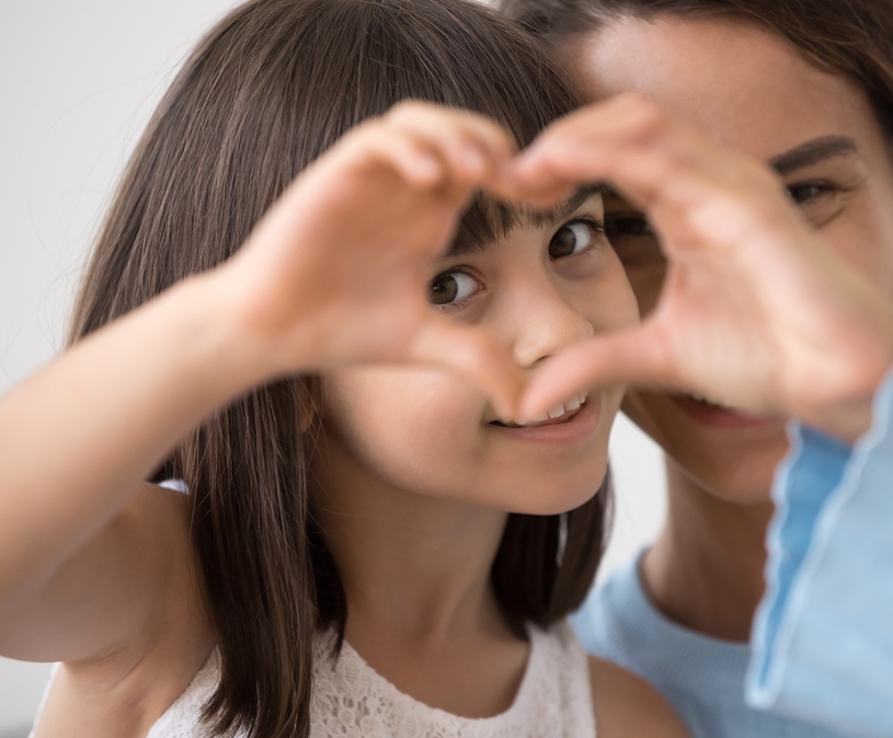 moeder en dochter maken samen een hartje van hun handen