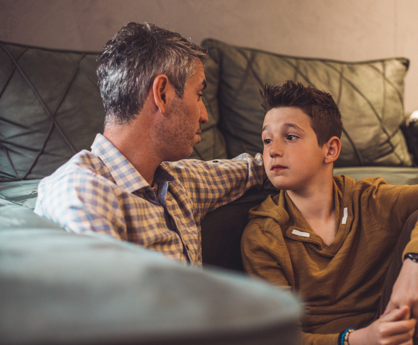 vader met grijs haar kijkt naar tiener zoon
