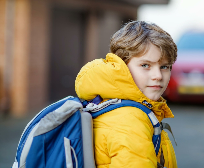 jongetje met rugzak en gele jas