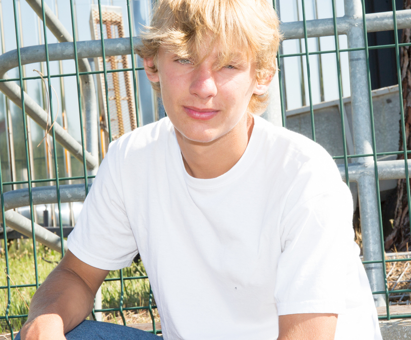 Blonde tienerjongen zit buiten