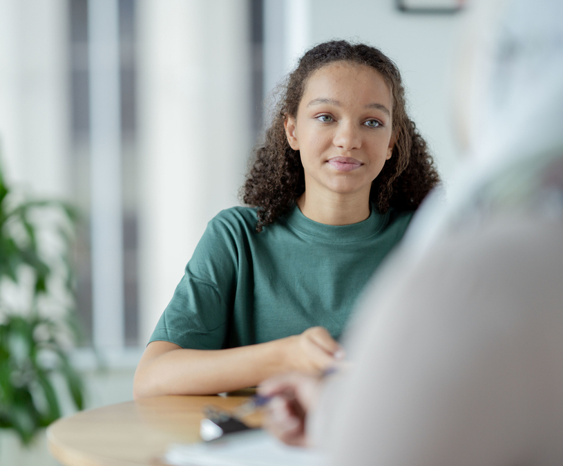 Meisje met krullen kijkt naar vrouw tegenover haar