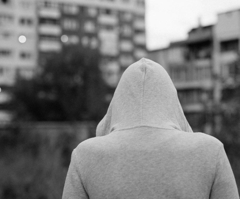 jongen met capuchon op staat met rug naar camera