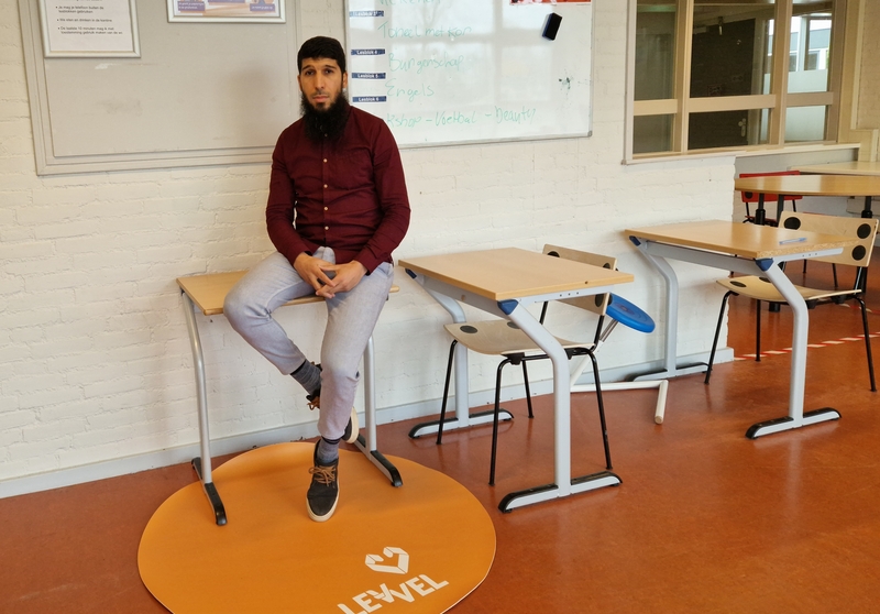 Abdelaziz Ouaouirst zit op een tafeltje in een klaslokaal van School2Care