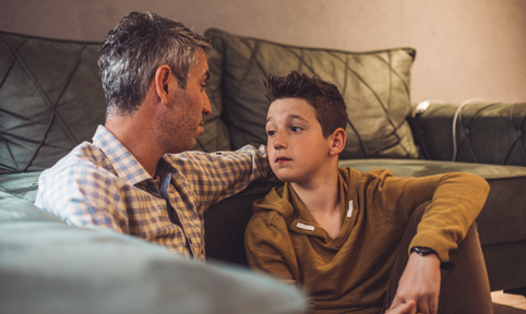 vader met grijs haar kijkt naar tiener zoon