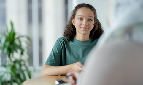 Meisje met krullen kijkt naar vrouw tegenover haar