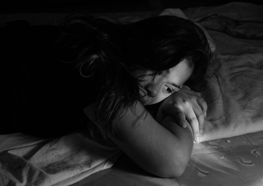 zwart wit foto van een meisje dat in bed ligt, kijkt verdrietig