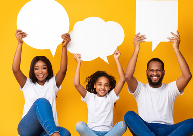een moeder, dochter en vader met een donkere huid houden borden in de vorm van een praatwolk omhoog
