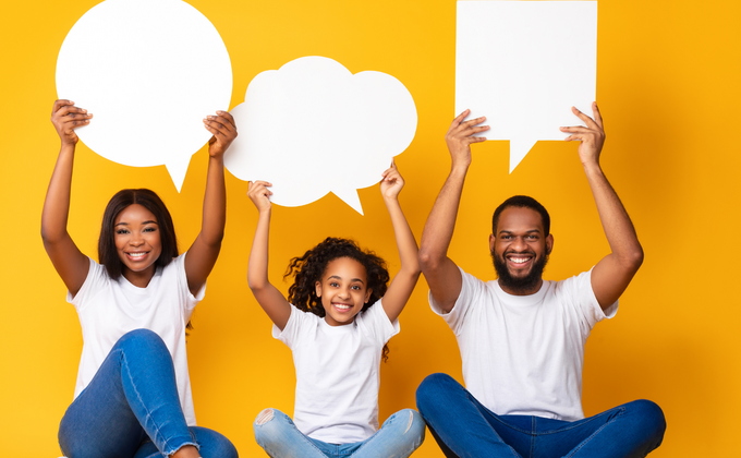 een moeder, dochter en vader met een donkere huid houden borden in de vorm van een praatwolk omhoog